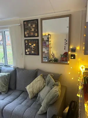 a living room with a gray couch and a mirror at Cabin in the Woods in Saint Erth