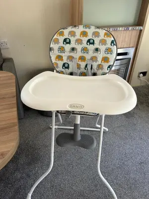 a white high chair with a seat with animals on it at Cabin in the Woods in Saint Erth