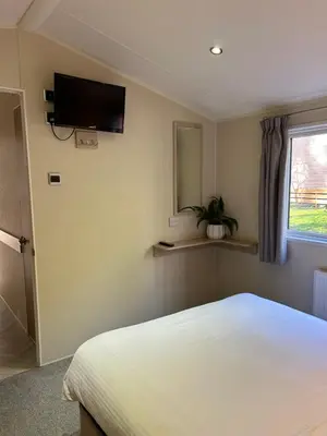 a bedroom with a bed and a tv on the wall at Cabin in the Woods in Saint Erth