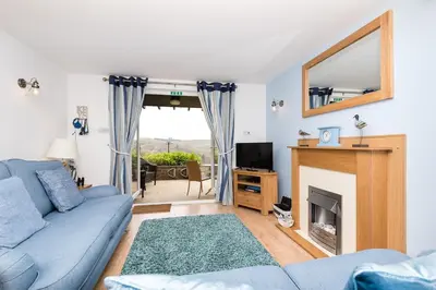 a living room with a blue couch and a fireplace at Rumsdale - Luxury Cottage in Looe
