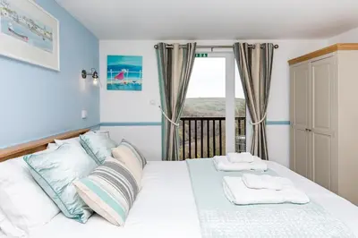 a bedroom with a white bed with towels on it at Rumsdale - Luxury Cottage in Looe