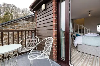a balcony with a bed and two chairs and a table at Rumsdale - Luxury Cottage in Looe