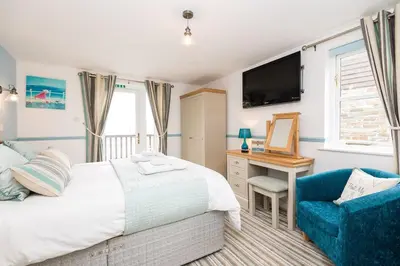 a bedroom with a bed and a desk and a tv at Rumsdale - Luxury Cottage in Looe