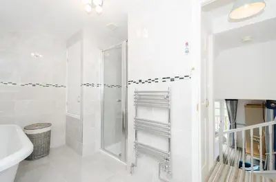 a white bathroom with a shower and a sink at Rumsdale - Luxury Cottage in Looe