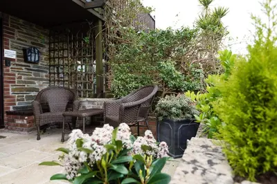 a patio with a table and chairs and plants at Rumsdale - Luxury Cottage in Looe