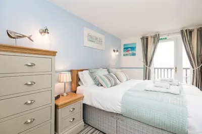 a bedroom with a bed with a dresser and a window at Rumsdale - Luxury Cottage in Looe