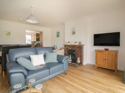 a living room with a blue couch and a fireplace at Orchard View in St Austell