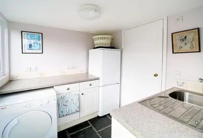 a white kitchen with a sink and a refrigerator at Hardys in Padstow