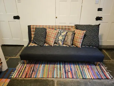 a couch with many pillows on top of a rug at Seahorse Cottage in Boscastle