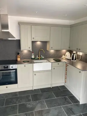 a kitchen with white cabinets and a sink at The Eliot Cottage in South Petherwin