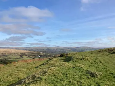 a view of a grassy hill with mountains in the background at The Eliot Cottage in South Petherwin