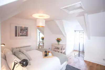 a bedroom with a white bed and a couch at The Attic, Tre-Pol-Pen in St Ives