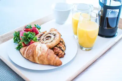 a plate of food with a croissant and fruit and orange juice at The Attic, Tre-Pol-Pen in St Ives