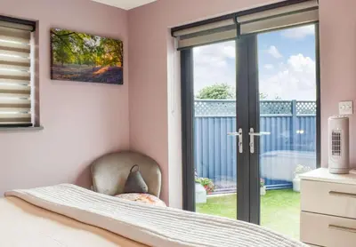 a bedroom with a sliding glass door to a balcony at Pentarow Barn in Falmouth