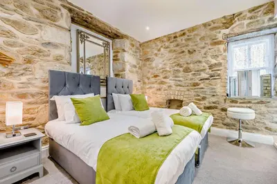 a bedroom with two beds and a stone wall at 5 Bed in Porthleven oc-t24809 in Porthleven