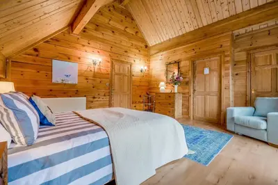 a bedroom in a log cabin with a bed and a chair at 3 Bed in Wadebridge oc-p34722 in Little Petherick