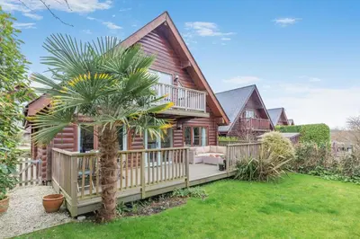 a log house with a porch and a palm tree at 3 Bed in Wadebridge oc-p34722 in Little Petherick