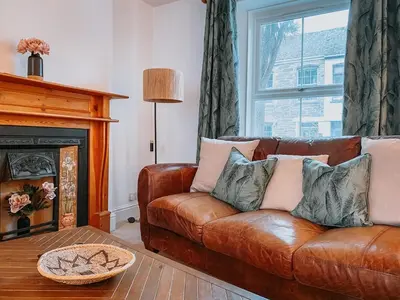 a living room with a brown leather couch and a fireplace at Twiga Cottage - Quiet 2 bed - Heart of town - Walk to beaches in Newquay