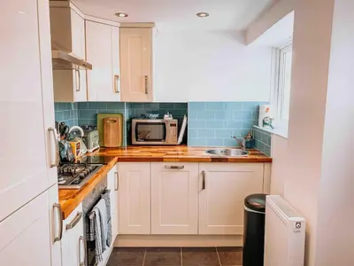 a small kitchen with a sink and a microwave at Twiga Cottage - Quiet 2 bed - Heart of town - Walk to beaches in Newquay