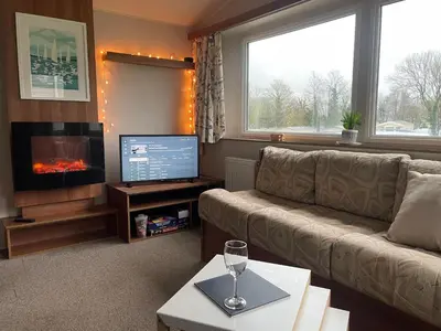 a living room with a couch and a flat screen tv at 26 The Green Captains Cabin in Crantock