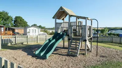 a playground with a green slide and a ladder at 26 The Green Captains Cabin in Crantock