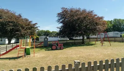 a park with a playground with a play equipment at 26 The Green Captains Cabin in Crantock