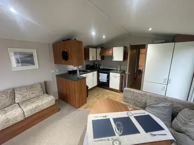 a living room with a couch and a kitchen at 26 The Green Captains Cabin in Crantock