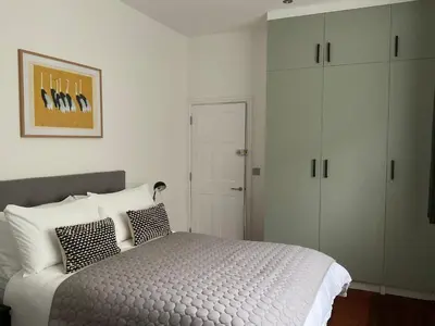 a bedroom with a white bed and a cabinet at 8, St Marys ,Central Truro Apartment, Long Stay Ready, 2 Bed 2 Bath in Truro