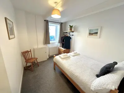 a bedroom with a bed with a black cat laying on it at The Old Corner Shop - Wellington Terrace in Falmouth