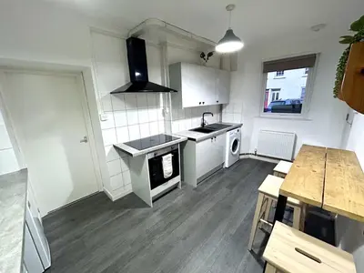 a white kitchen with a sink and a stove at The Old Corner Shop - Wellington Terrace in Falmouth