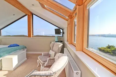 a room with a bed and two chairs and a window at Sea View House in Newquay