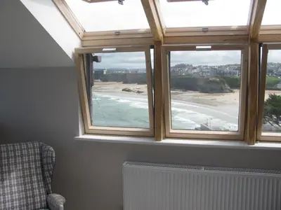 a room with three windows with a view of a beach at Sea View House in Newquay