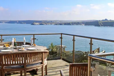 a wooden deck with a table and a view of the ocean at Sea View House in Newquay