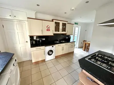 a kitchen with white cabinets and a washing machine at The Blue House - Godolphin - Large Spacious Home in Falmouth