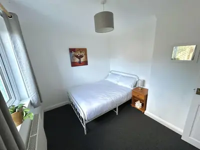 a small room with a bed and a night stand at The Blue House - Godolphin - Large Spacious Home in Falmouth