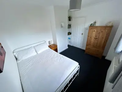 a bedroom with a white bed and a wooden cabinet at The Blue House - Godolphin - Large Spacious Home in Falmouth