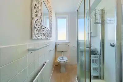 a bathroom with a toilet and a glass shower at Sealight Cottage in St Ives