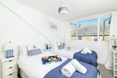 two twin beds in a room with windows at Sealight Cottage in St Ives