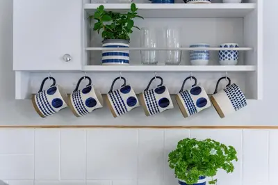 a kitchen with blue and white cups and plants at Sealight Cottage in St Ives