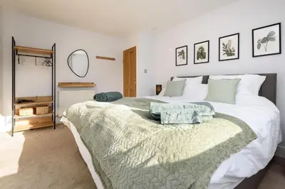 a bedroom with a large white bed and a mirror at Custom House - Modern town centre house, sea views, two minutes to the beach in Looe