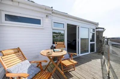 a patio with two chairs and a table on a deck at Custom House - Modern town centre house, sea views, two minutes to the beach in Looe