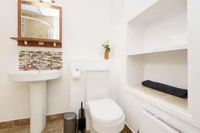 a white bathroom with a toilet and a sink at Custom House - Modern town centre house, sea views, two minutes to the beach in Looe