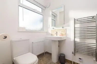 a white bathroom with a toilet and a sink at Custom House - Modern town centre house, sea views, two minutes to the beach in Looe