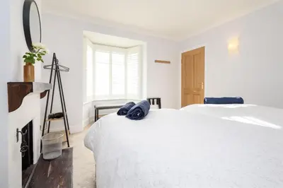 a white bedroom with a bed and a fireplace at Custom House - Modern town centre house, sea views, two minutes to the beach in Looe