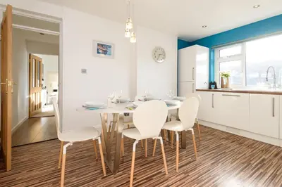 a kitchen and dining room with a white table and chairs at Custom House - Modern town centre house, sea views, two minutes to the beach in Looe