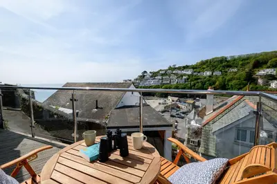 a balcony with a table and a view of a town at Custom House - Modern town centre house, sea views, two minutes to the beach in Looe