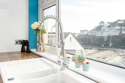 a white sink in a kitchen with a window at Custom House - Modern town centre house, sea views, two minutes to the beach in Looe