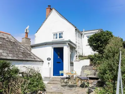 a white cottage with a blue door at Rose Hill Cottage in Port Isaac