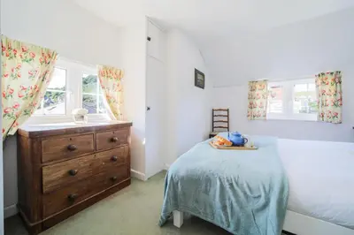 a bedroom with a bed and a sink and a dresser at Rose Hill Cottage in Port Isaac