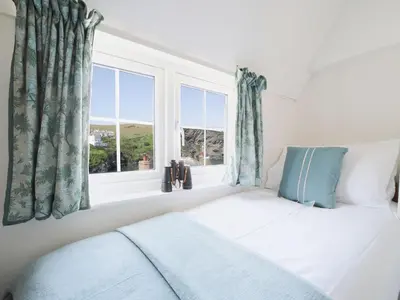 a bedroom with a bed and a window at Rose Hill Cottage in Port Isaac